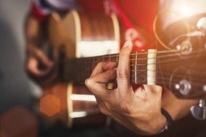 mans hands playing country music on guitar