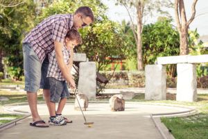 father helping young son play mini golf in Pigeon Forge