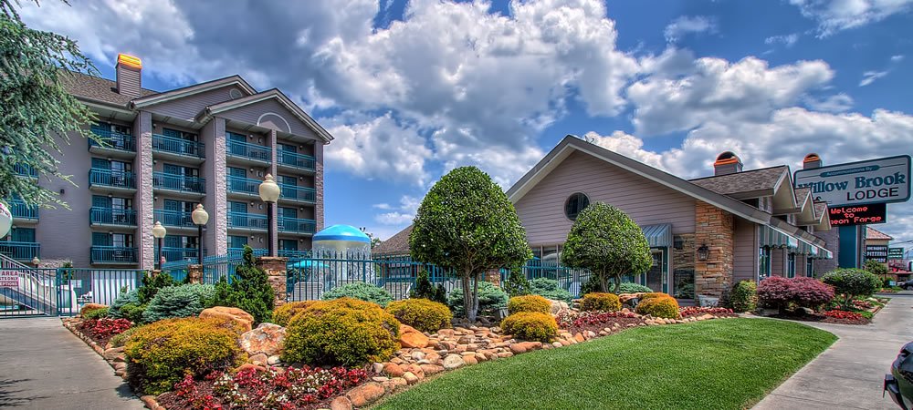 exterior view of lodge, green lawn in front and rock garden with trees