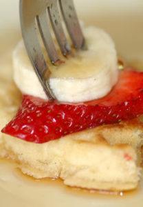 Fork full of belgium waffle, strawberry and banana.